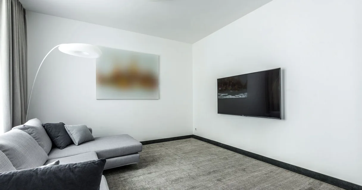 Sala moderna com televisão de tela plana fixada na parede, cenário do IPTV em 4K
