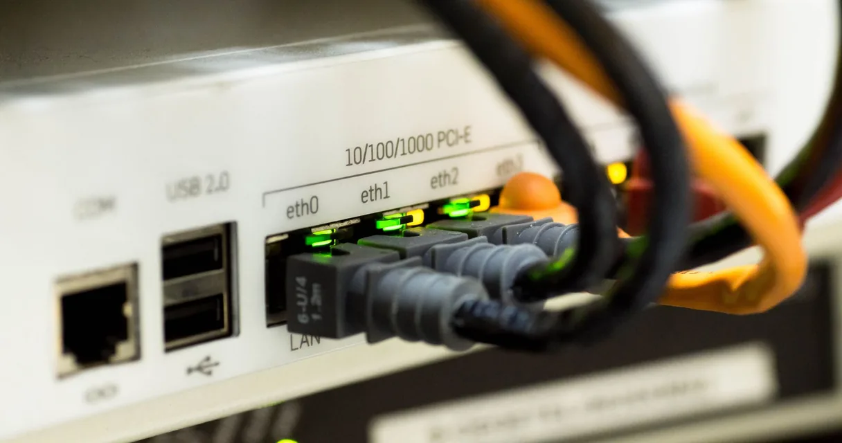 Cabos de rede conectados às portas de um roteador, ilustrando o jitter no IPTV