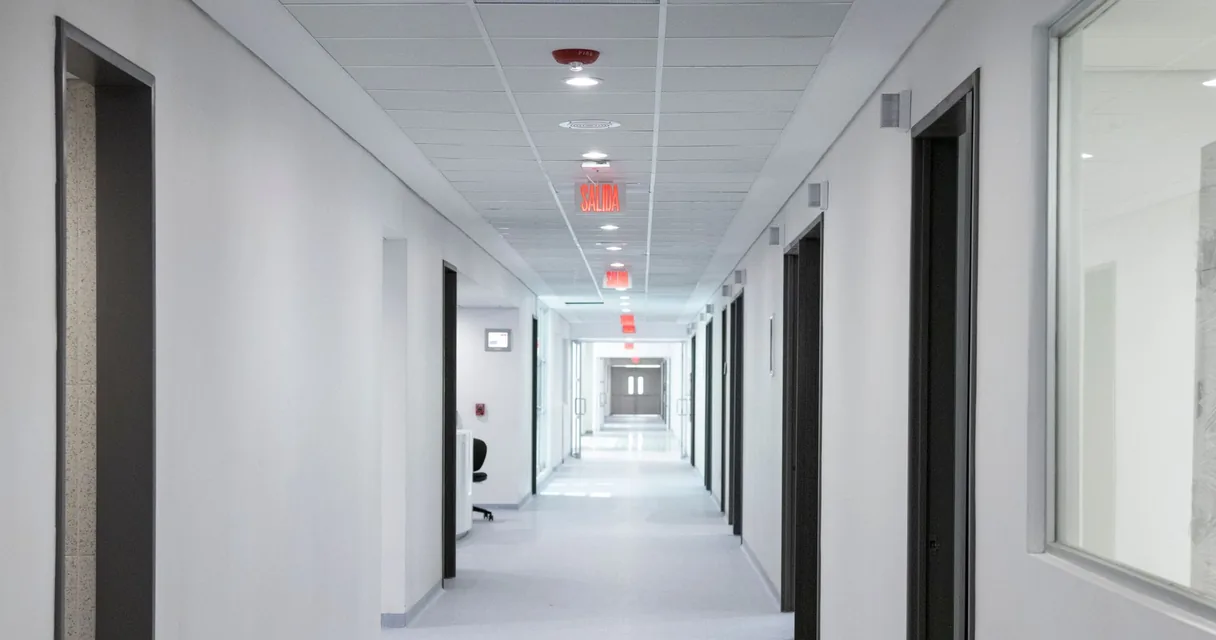 Corredor claro e vazio de hospital com portas laterais, ilustrando o laudo de endoscopia