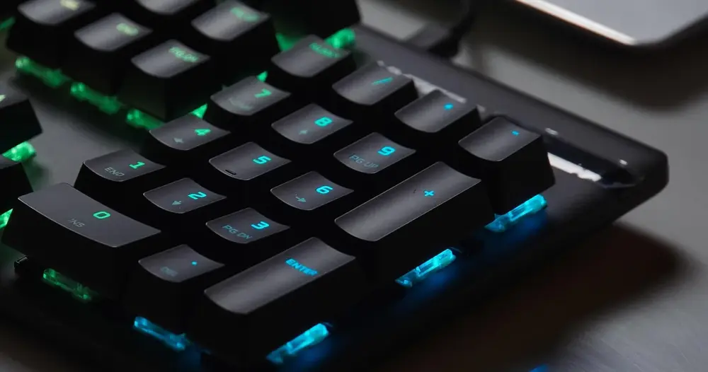 Teclado mecânico gamer com teclas iluminadas, ilustrando sites de letras personalizadas para nick