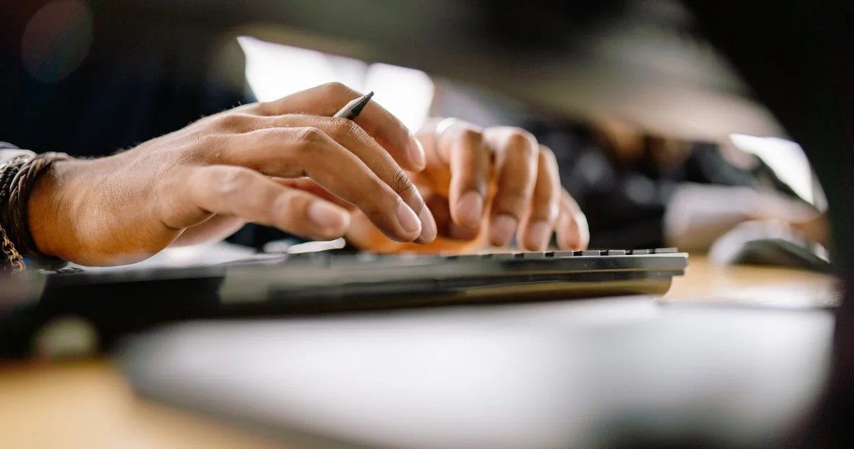 Mãos digitando num teclado de computador, em close
