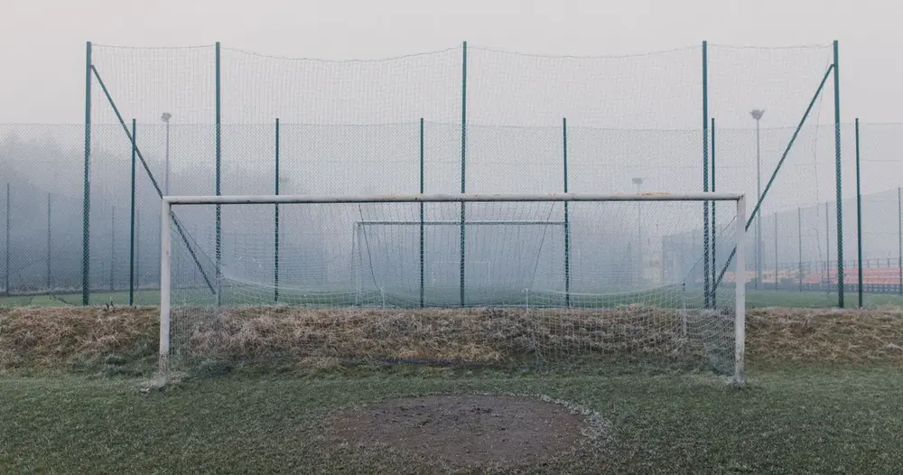 Goleira de futebol com rede em campo de grama na neblina, cenário para um teste IPTV futebol